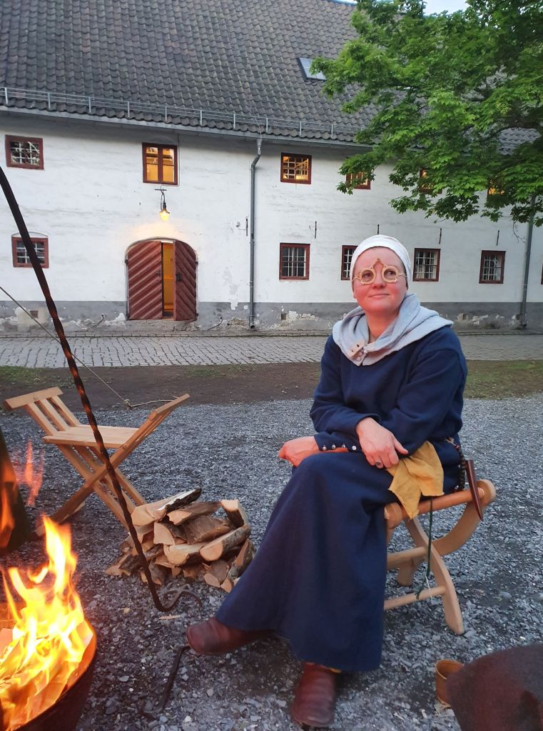 Lena ved leirbål med middelalderbriller