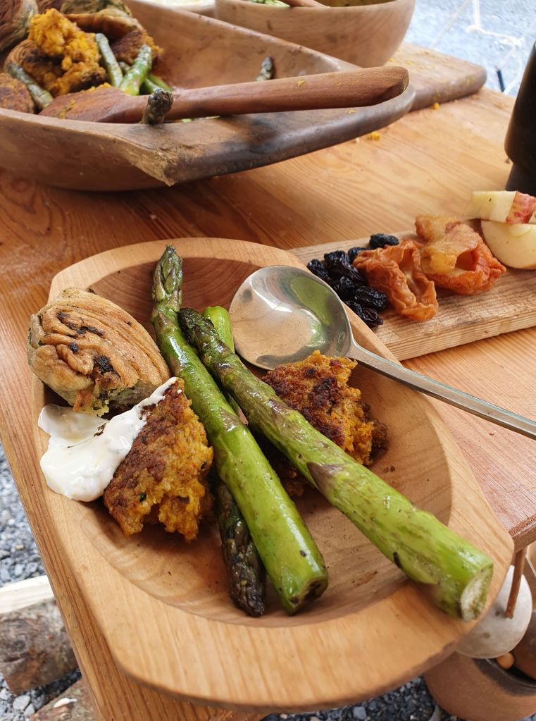 Nydelig mat, asparges og brød laget i gryter over bålet